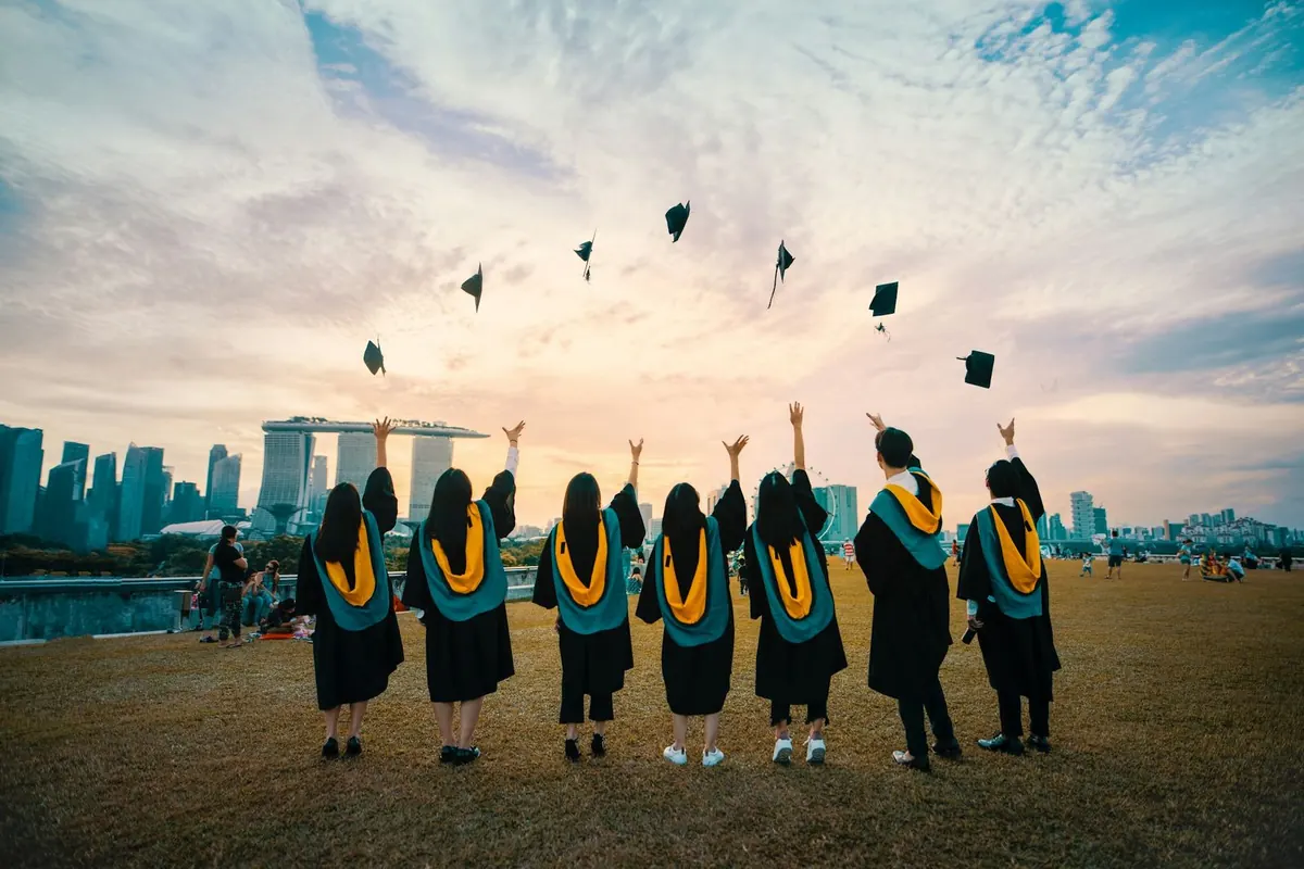 Graduates throwing their caps in the air at sunset