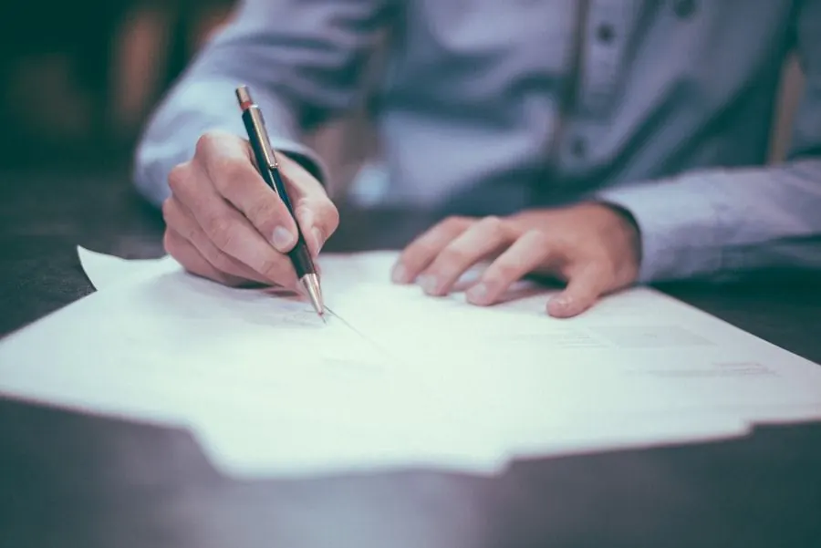 A hand filling in application forms with a pen